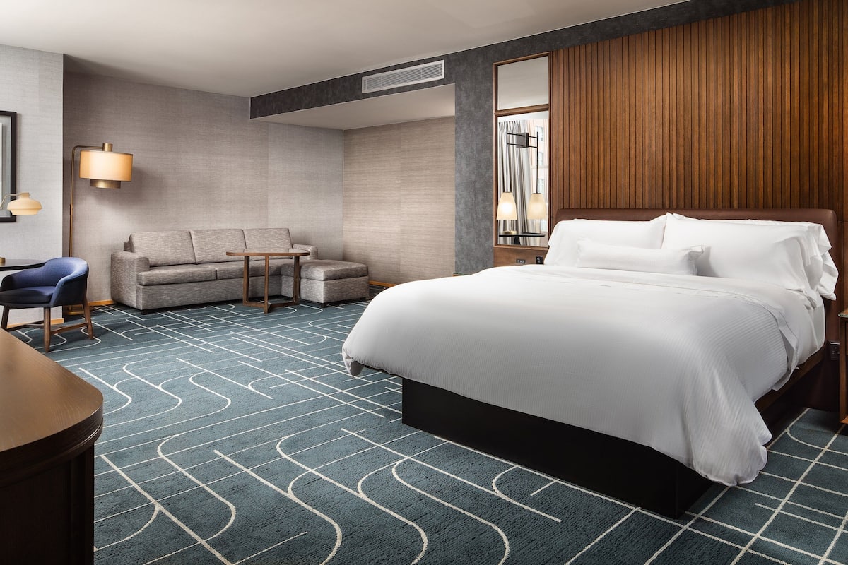 Ein Hotelzimmer mit einem großen Bett, einem Sofa, einem Schreibtisch und einer Lampe.
