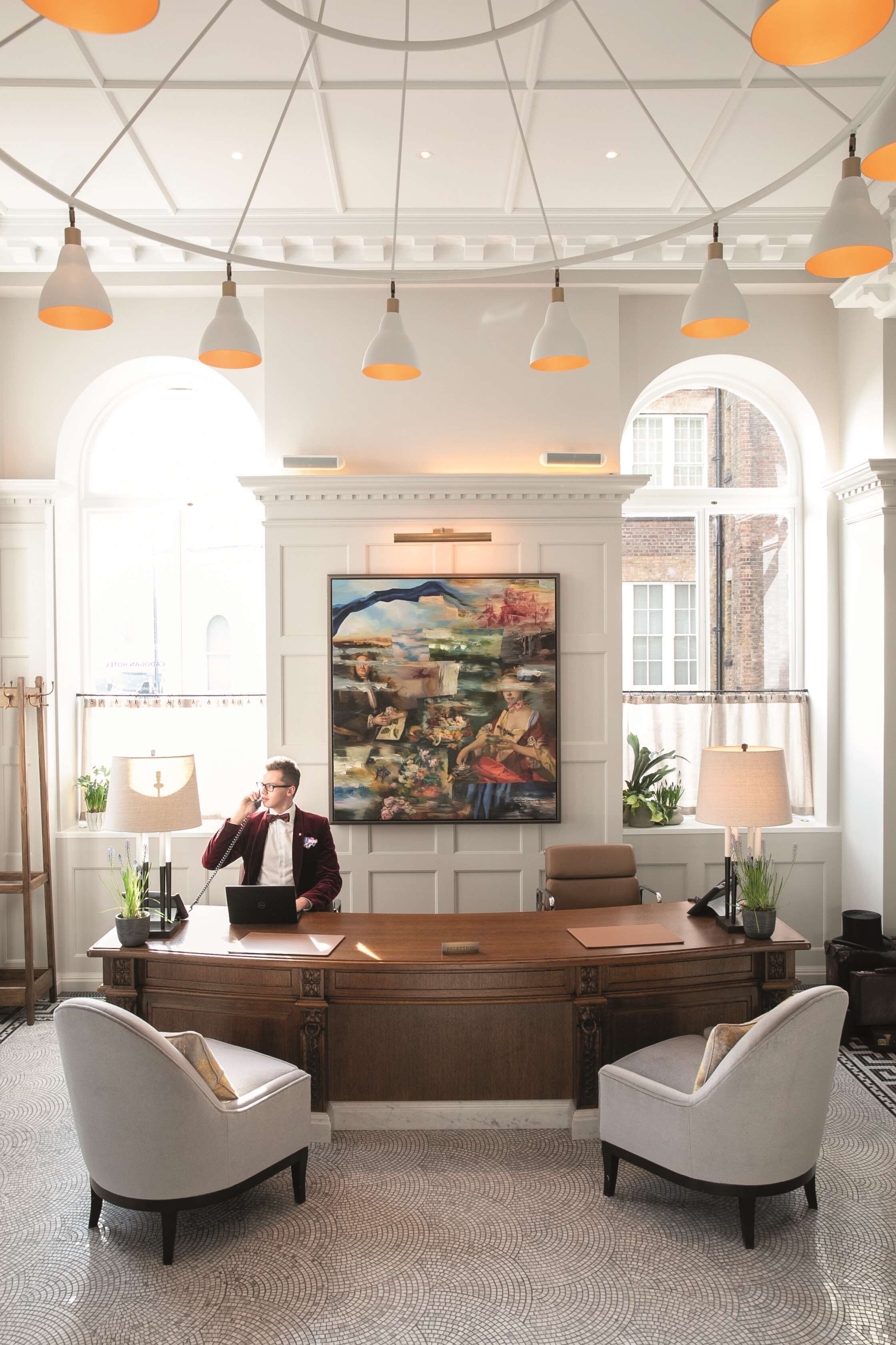 A well-lit office with a wooden desk, two chairs, and a large painting on the wall.