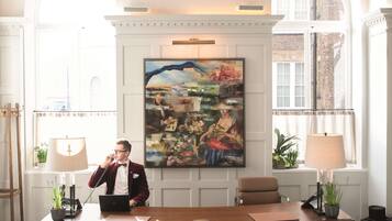 A well-lit office with a wooden desk, two chairs, and a large painting on the wall.