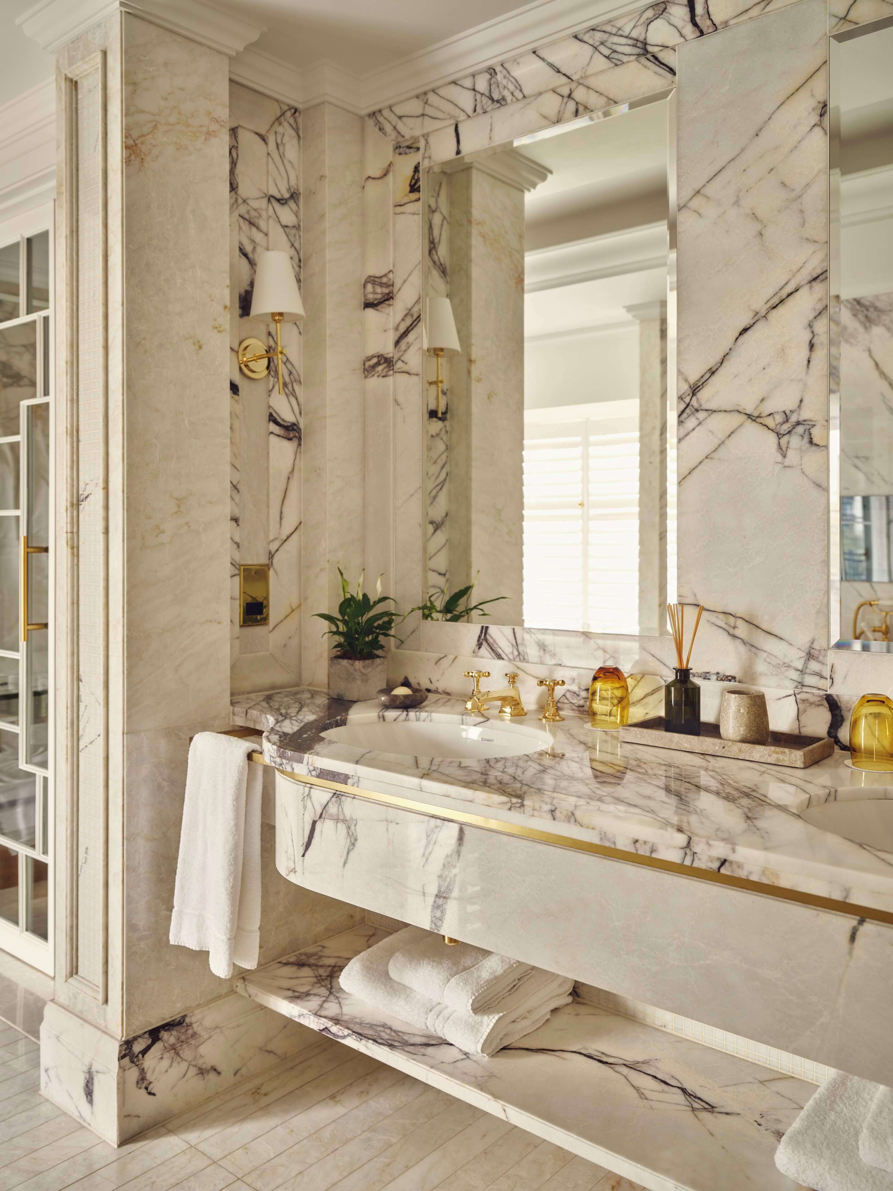 A bathroom with marble countertops, a sink, a mirror, and a towel rack.