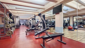 Une salle de sport équipée de matériel de musculation, de bancs d’exercice et d’un mur recouvert de miroirs.