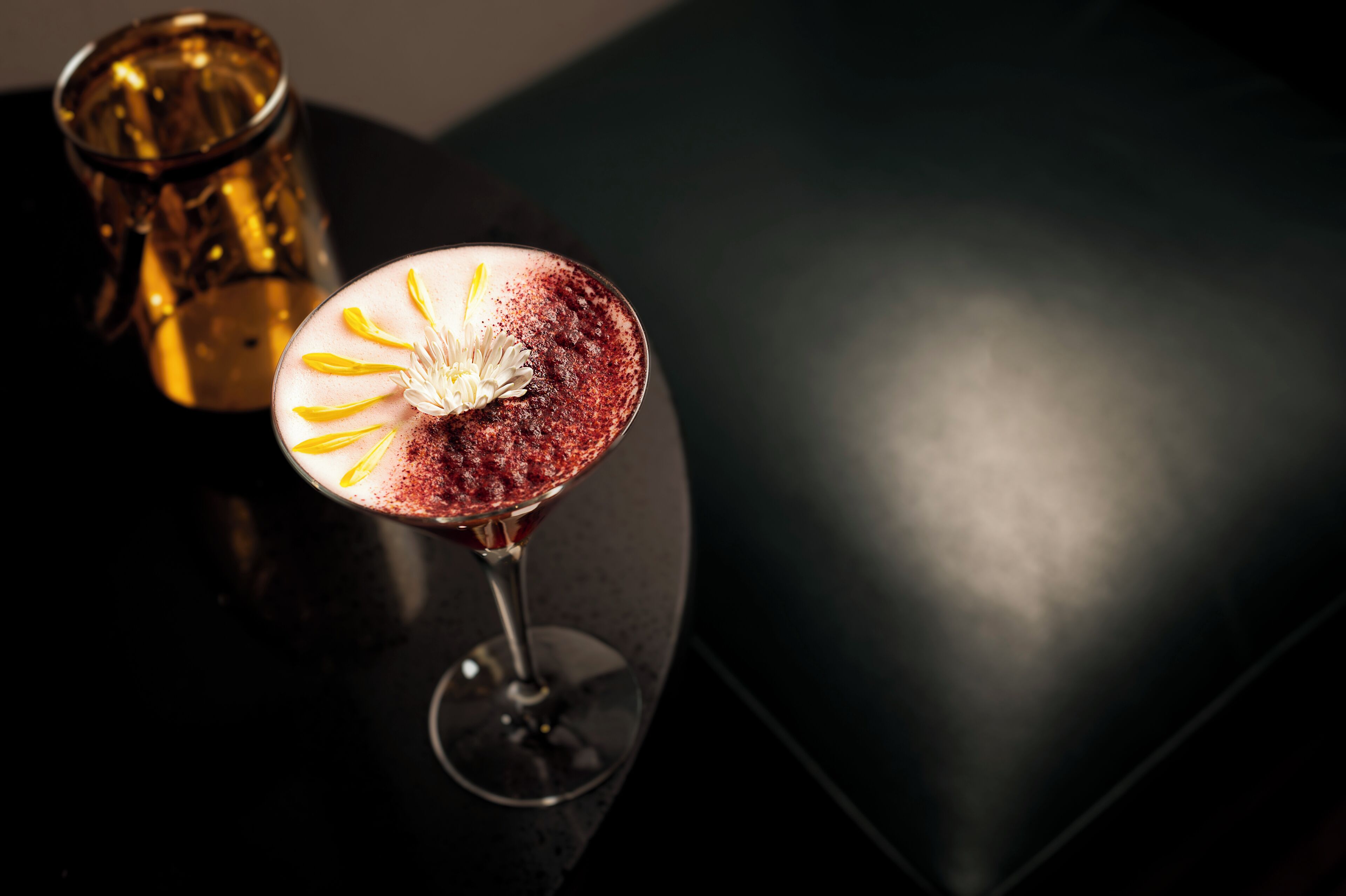 Ein Martini-Glas mit einer Blüte auf dunklem Untergrund.