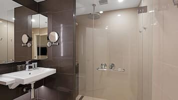 A modern bathroom with a glass-enclosed shower, a sink with a mirror, and a towel rack.