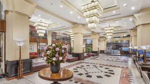 Un hall d’entrée spacieux avec une table ronde centrale, plusieurs coins salon et un motif décoratif sur le sol.