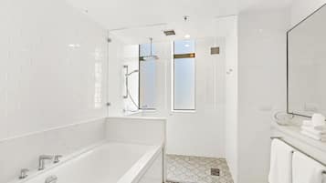 Une salle de bain moderne équipée d’une baignoire, d’une douche et d’un espace de douche séparé par des parois en verre.