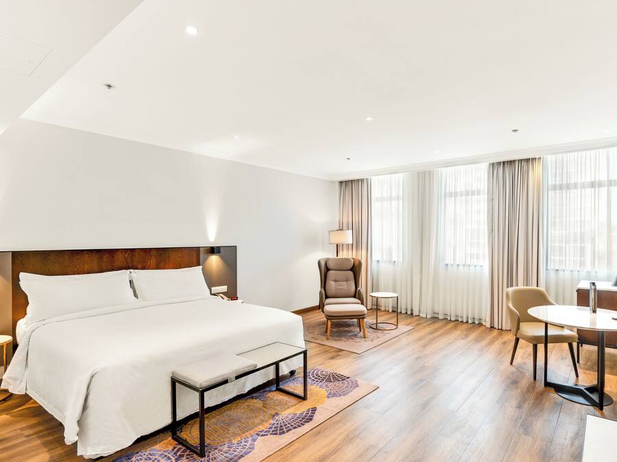 Een hotelkamer met een groot bed, een bureau, een stoel en een klein tafeltje.