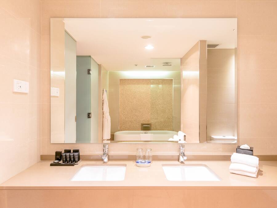 A bathroom with two sinks, a mirror, and a shower area.