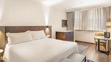 Ein Hotelzimmer mit einem großen Bett, einem Schreibtisch, einem Sessel und einem kleinen Tisch.