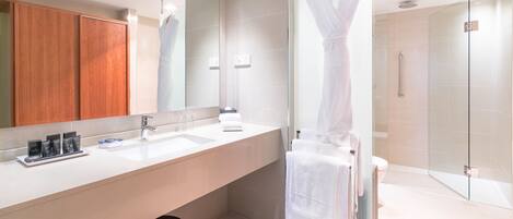 Un baño moderno con un espejo grande, un tocador con lavabo y una cabina de ducha de vidrio.