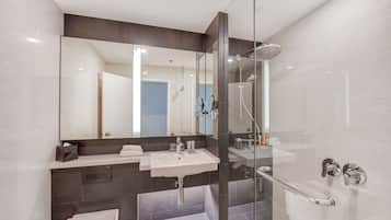 Une salle de bain moderne avec une douche à parois de verre, un lavabo blanc et un grand miroir.
