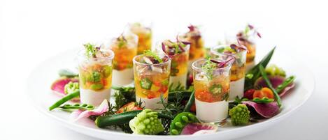 A white plate with several clear glasses containing layered food and garnishes.