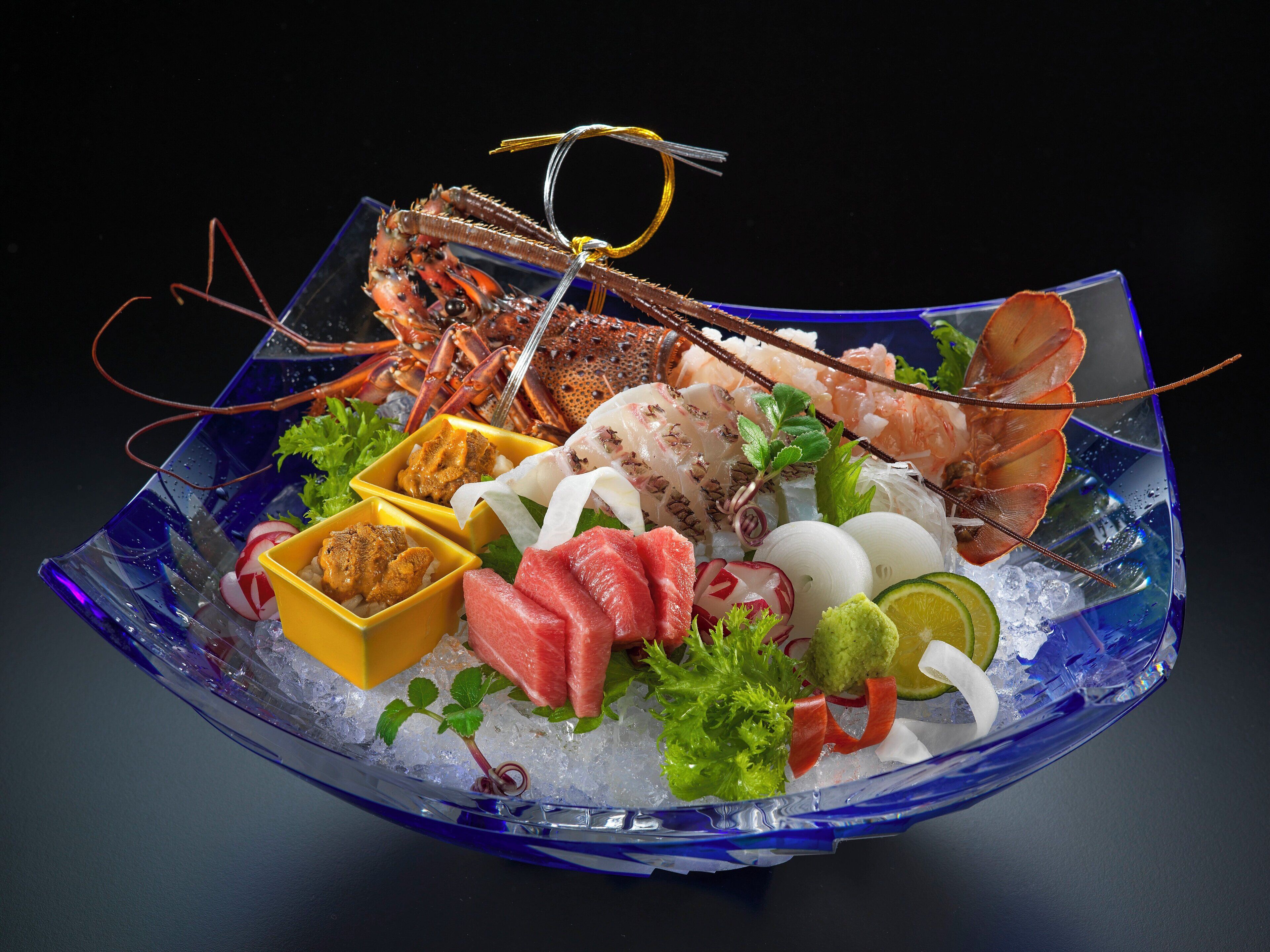 A seafood platter with various items like lobster, shrimp, and sashimi on ice, accompanied by condiments and garnishes.