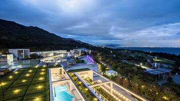 Un hotel moderno con piscina, jardines ajardinados y vista al mar.