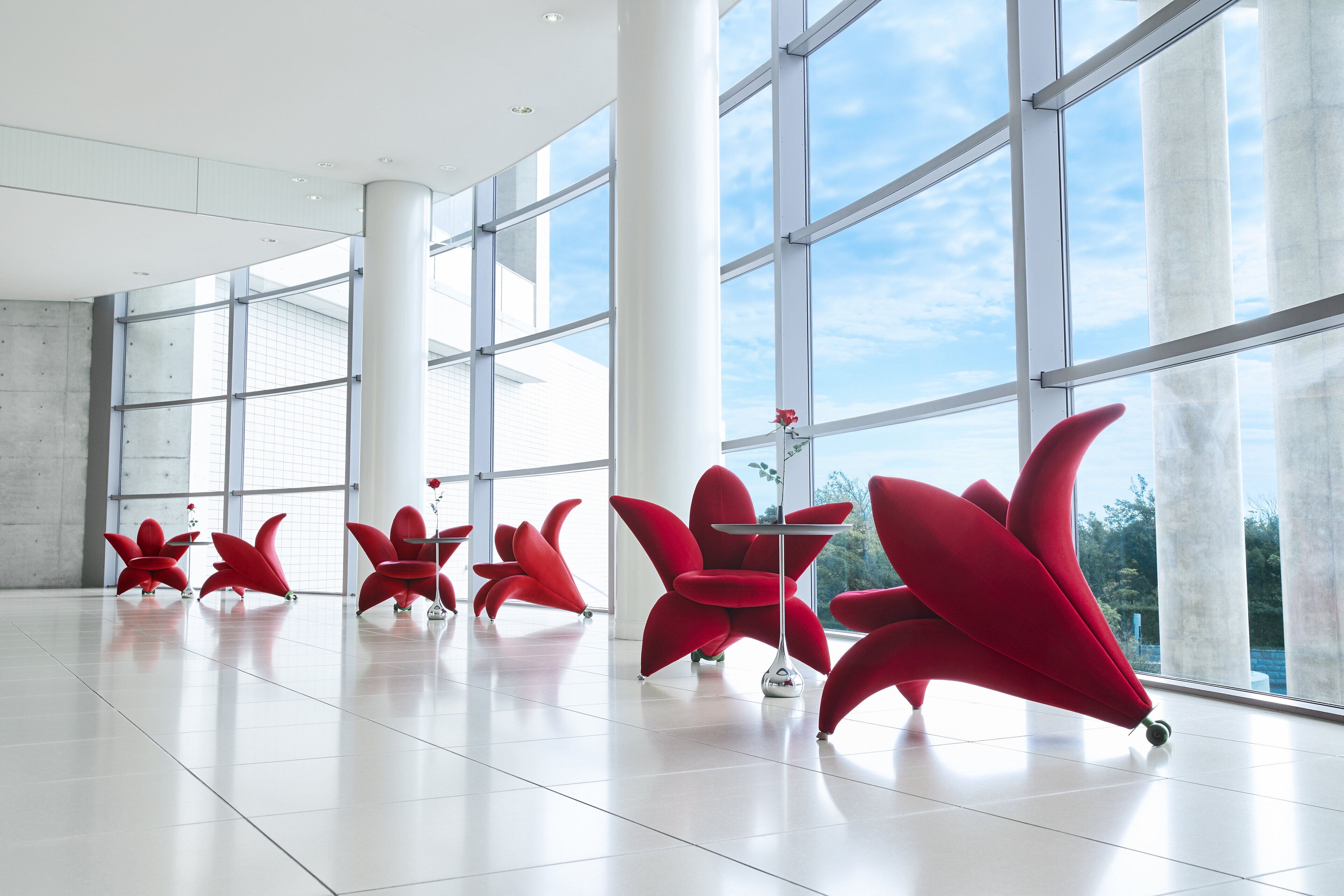 Un interior espacioso con amplias ventanas, sillas rojas modernas y un diseño minimalista.