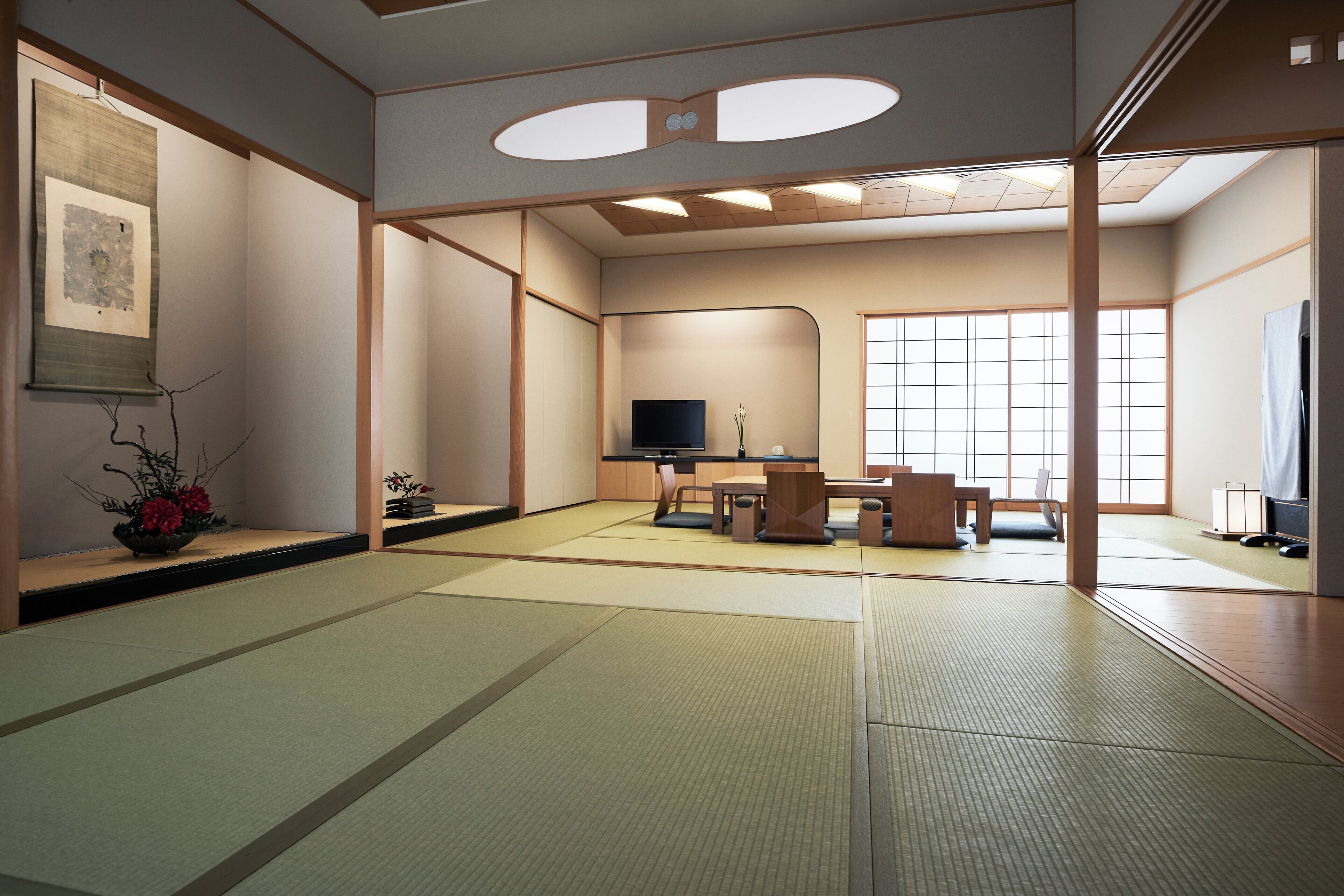A traditional tatami mat room with a television, tatami mats, a small table, and a window.