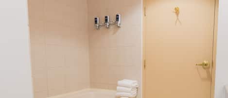 Un baño con una bañera, un inodoro y un lavabo. Hay toallas apiladas al lado de la bañera.