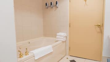 A bathroom with a bathtub, a toilet, and a sink. There are towels stacked on the bathtub.