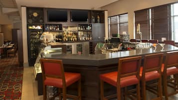 A bar area with a central island, bar stools, and a variety of bottles.