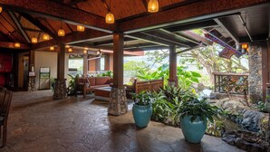 A covered outdoor area with stone flooring, wooden furniture, and potted plants. - Hanalei Bay Resort (Princeville)
