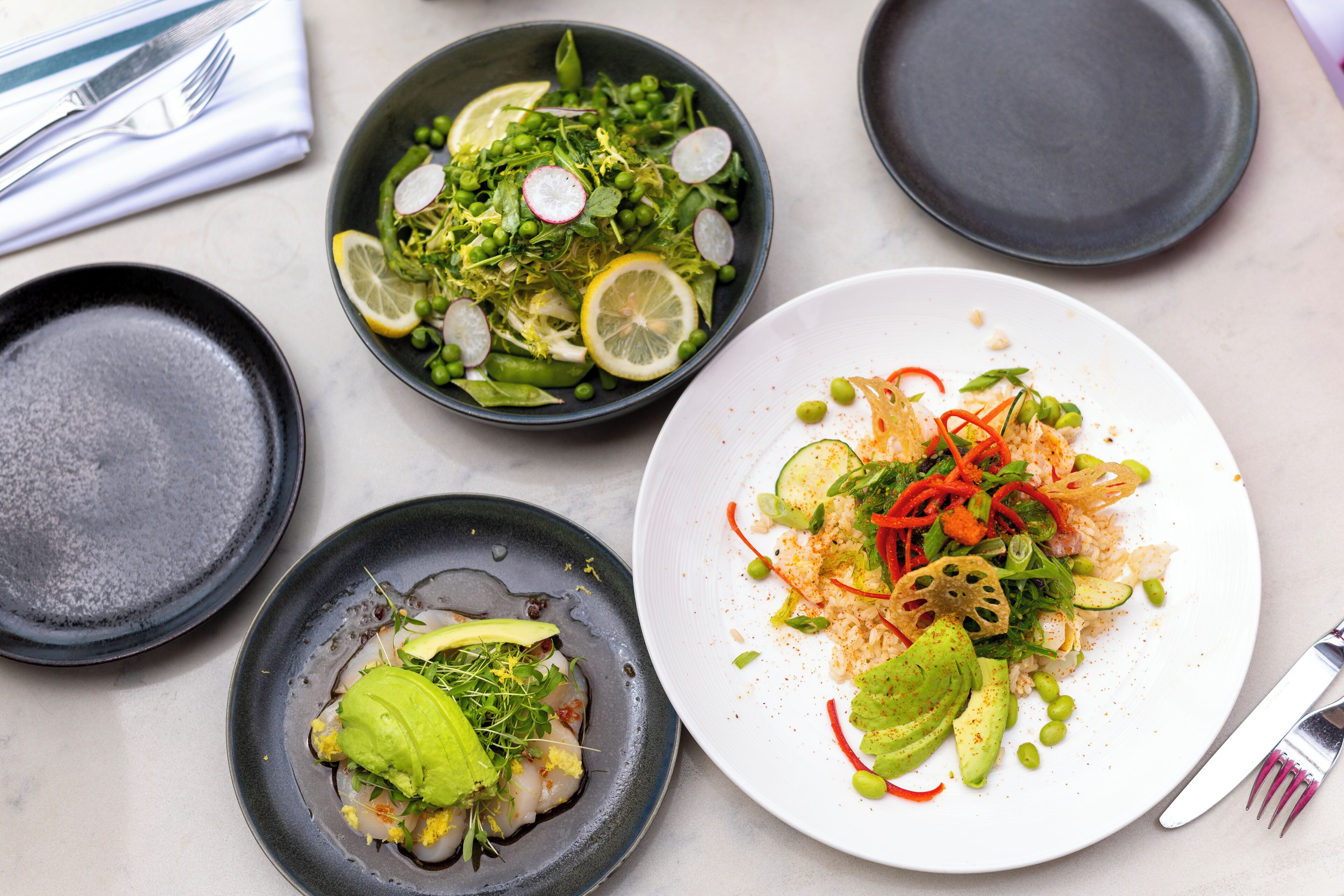 A dining table with four plates of food, each with different dishes.