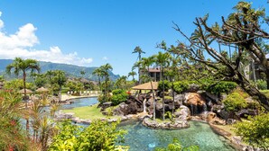 A resort with a clear pool, palm trees, and a waterfall. - Hanalei Bay Resort (Princeville)