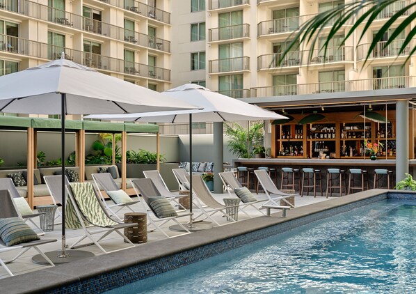 Una piscina al aire libre, camas de piscina con cargo, sombrillas