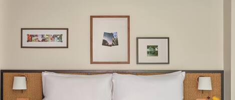 A hotel room with a large bed, two bedside tables, and three framed pictures on the wall.