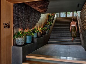 Una escalera con plantas en macetas, un muro de madera con un letrero y una persona bajando.