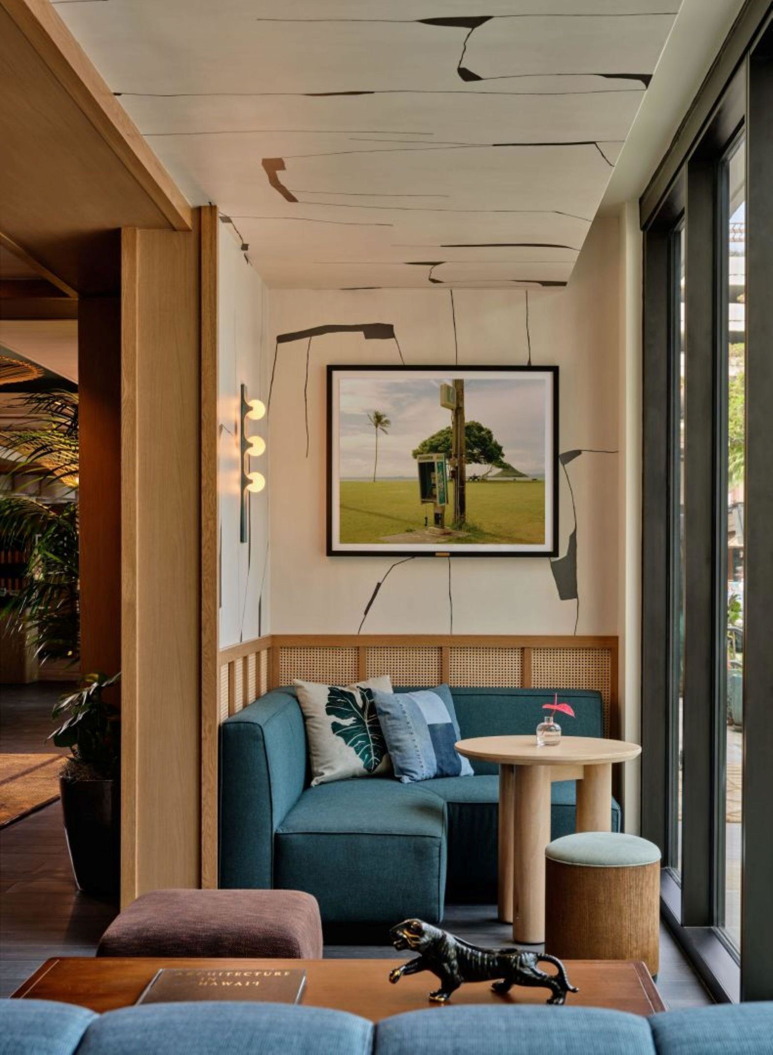 A modern lounge area with a sofa, a small round table, and a framed landscape painting.