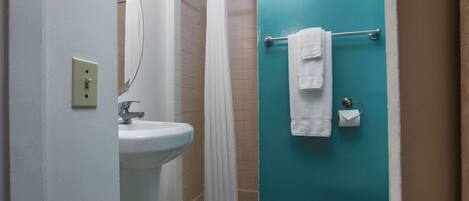 A bathroom with a white sink, a shower with a white curtain, and a toilet.