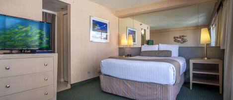 A hotel room with a large bed, a television, a dresser, and a mirror.