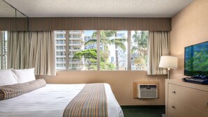 A hotel room with a large bed, a dresser, a television, and a window with curtains. - Aqua Aloha Surf Waikiki (Honolulu)