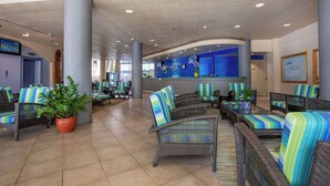 A hotel lobby with wicker furniture, potted plants, and a reception area. - Aqua Aloha Surf Waikiki (Honolulu)