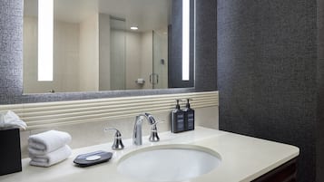A modern bathroom with a large mirror, a sink, and two hand dryers.