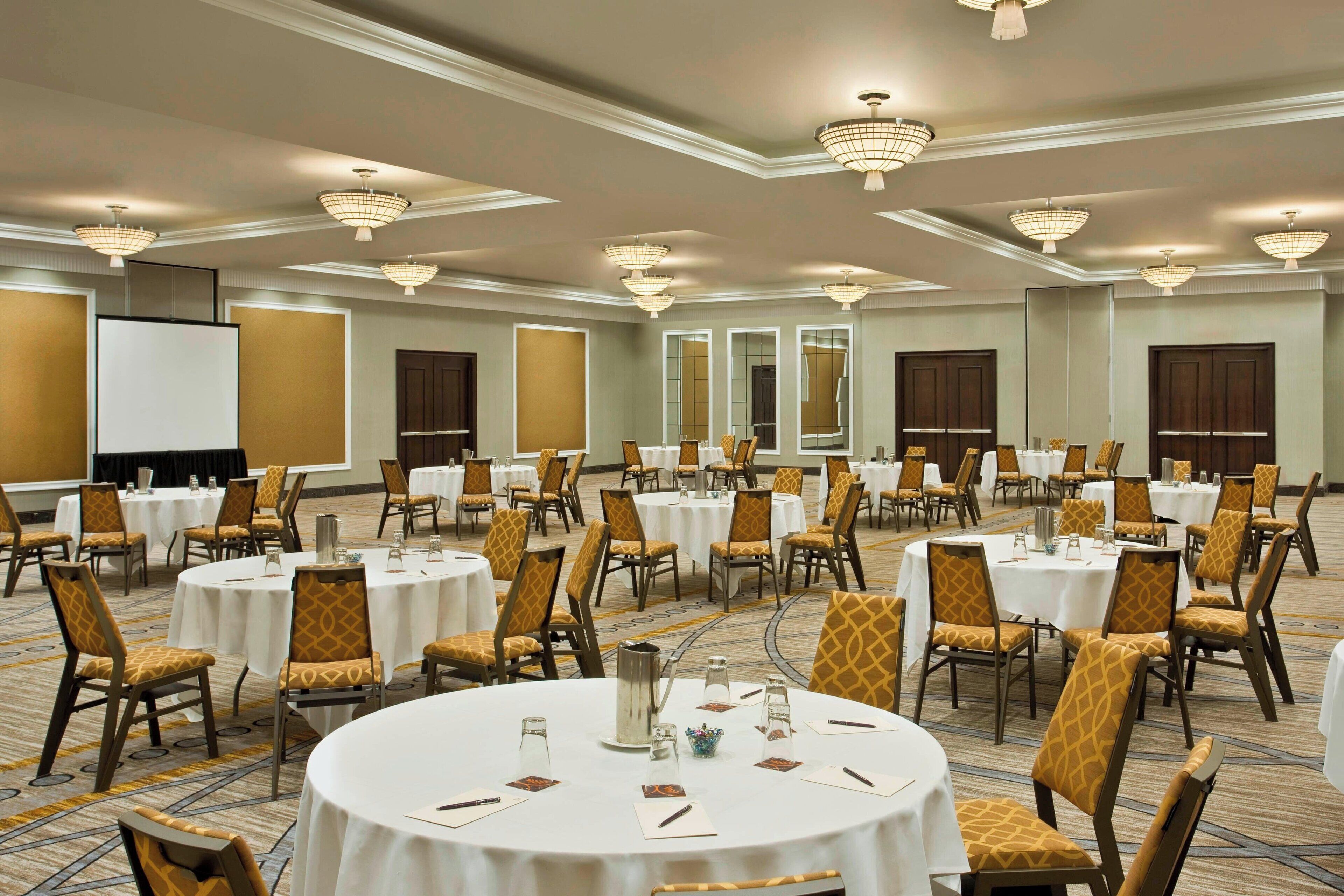 Un salón de banquetes con mesas redondas, sillas y candelabros.