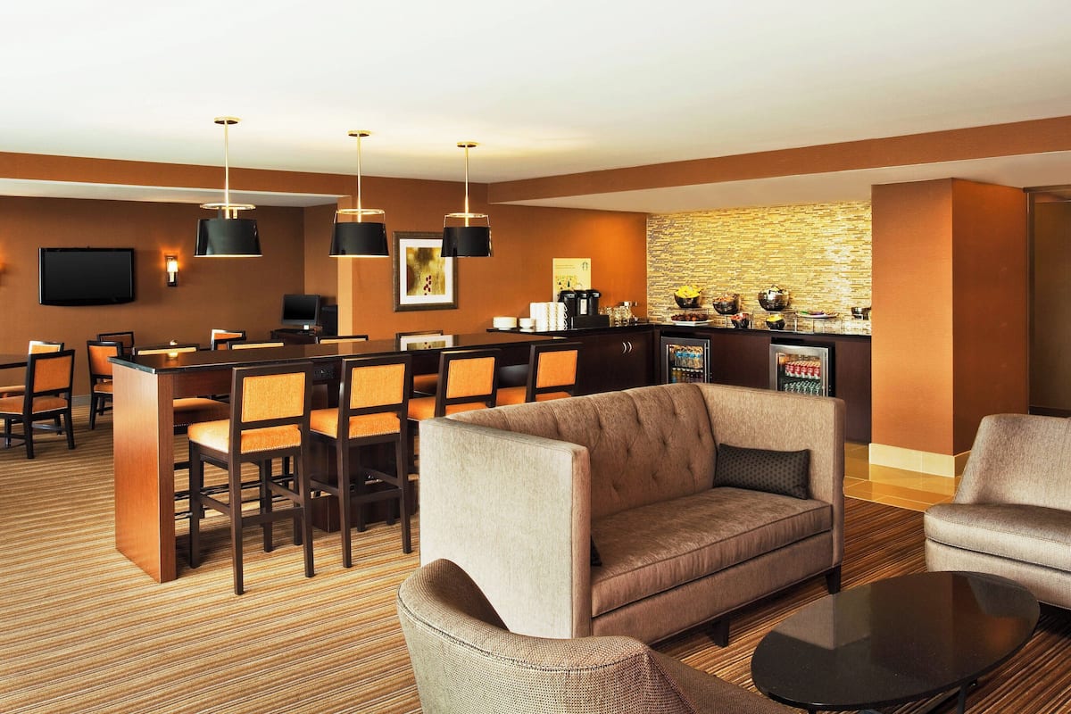 A hotel lobby with a bar area, seating, and a television.