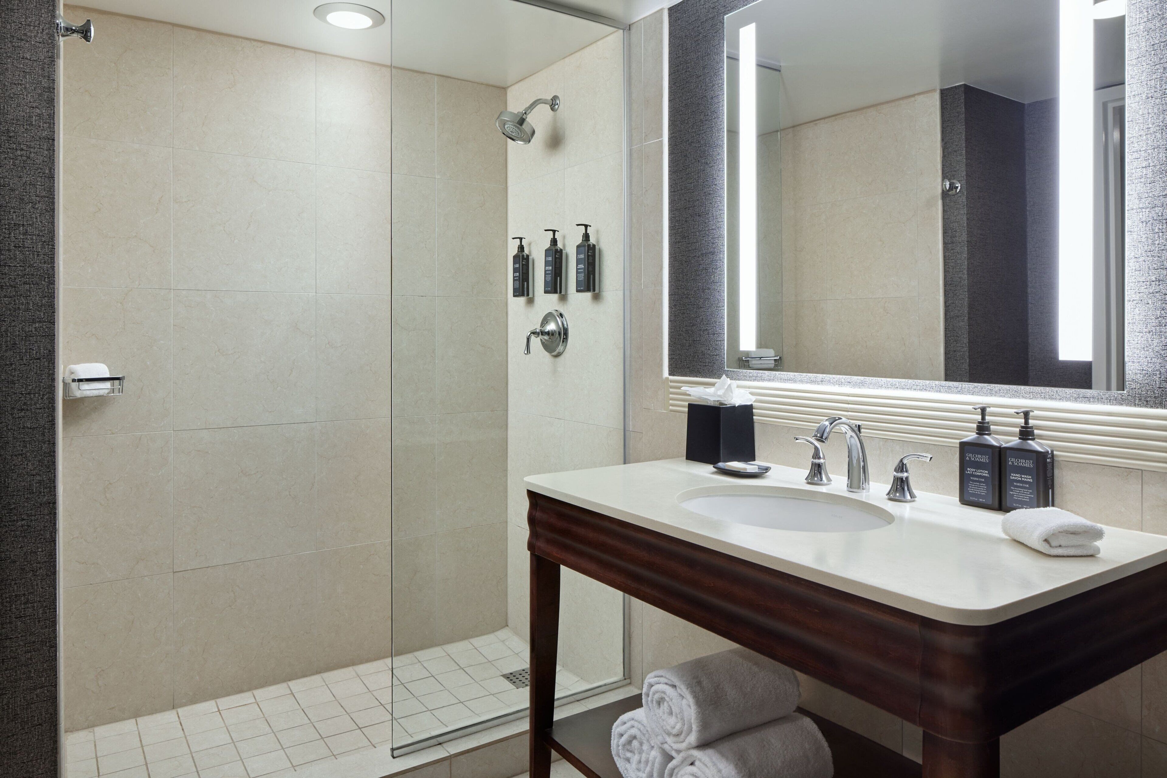 Une salle de bain moderne avec une douche à parois de verre, un meuble-lavabo avec un miroir et des articles de toilette.