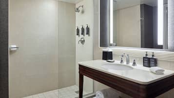 Une salle de bain moderne avec une douche à parois de verre, un meuble-lavabo avec un miroir et des articles de toilette.