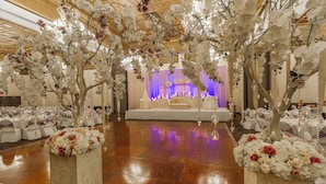 A wedding reception area with a stage, floral decorations, and tables set for guests.