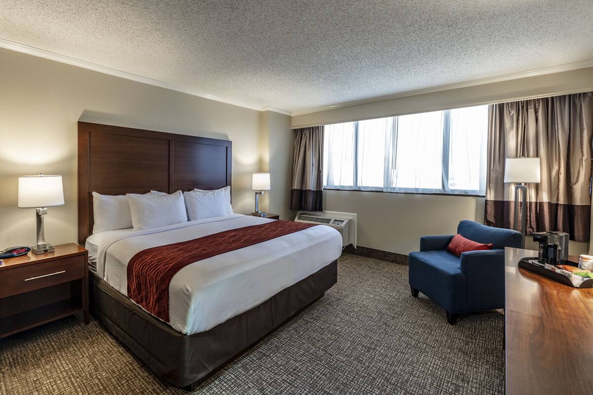 A hotel room with a large bed, bedside tables, a desk, and a chair.