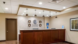 A reception desk with a stone-textured wall, a logo, and a digital screen.