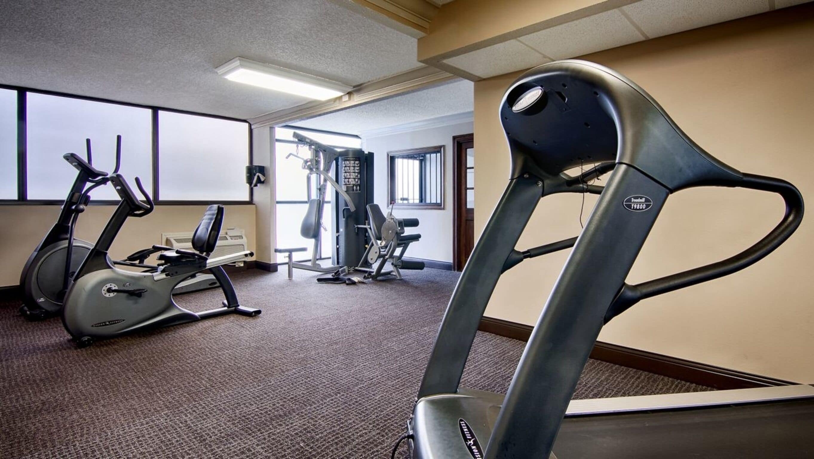 Un gimnasio con bicicletas estáticas, cinta de correr y máquinas de pesas.