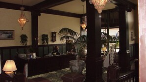 A lobby with a reception desk, large potted plants, and ornate chandeliers. - Geiser Grand Hotel (Baker City)