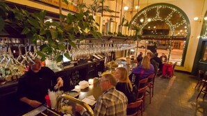 A bar area with a bartender, seated guests, and a bar counter with glasses and bottles. - Geiser Grand Hotel (Baker City)