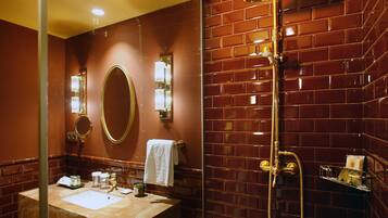 A bathroom with a marble sink, a large mirror, a towel rack, and a shower with a gold fixture.