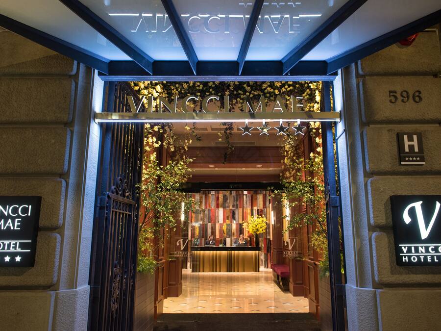 The entrance to Vincci Mael Hotel with a reception desk, a sign with the hotel name, and a number '596' on the wall.