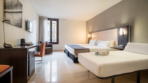 Une chambre d’hôtel avec deux lits, un bureau avec un ordinateur, une chaise et une fenêtre avec des rideaux.
