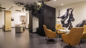 Un intérieur moderne comprenant un espace salon, une grande peinture abstraite et une installation végétale.