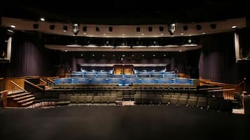 A theater with tiered seating, a stage, and a proscenium arch.