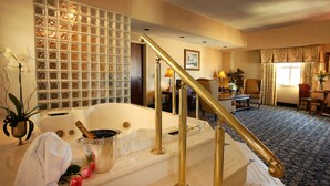 A hotel room with a large bathtub, a staircase with golden railings, a dining area with a table and chairs, and a decorative wall with a grid pattern. - The Claridge Hotel (Atlantic City)